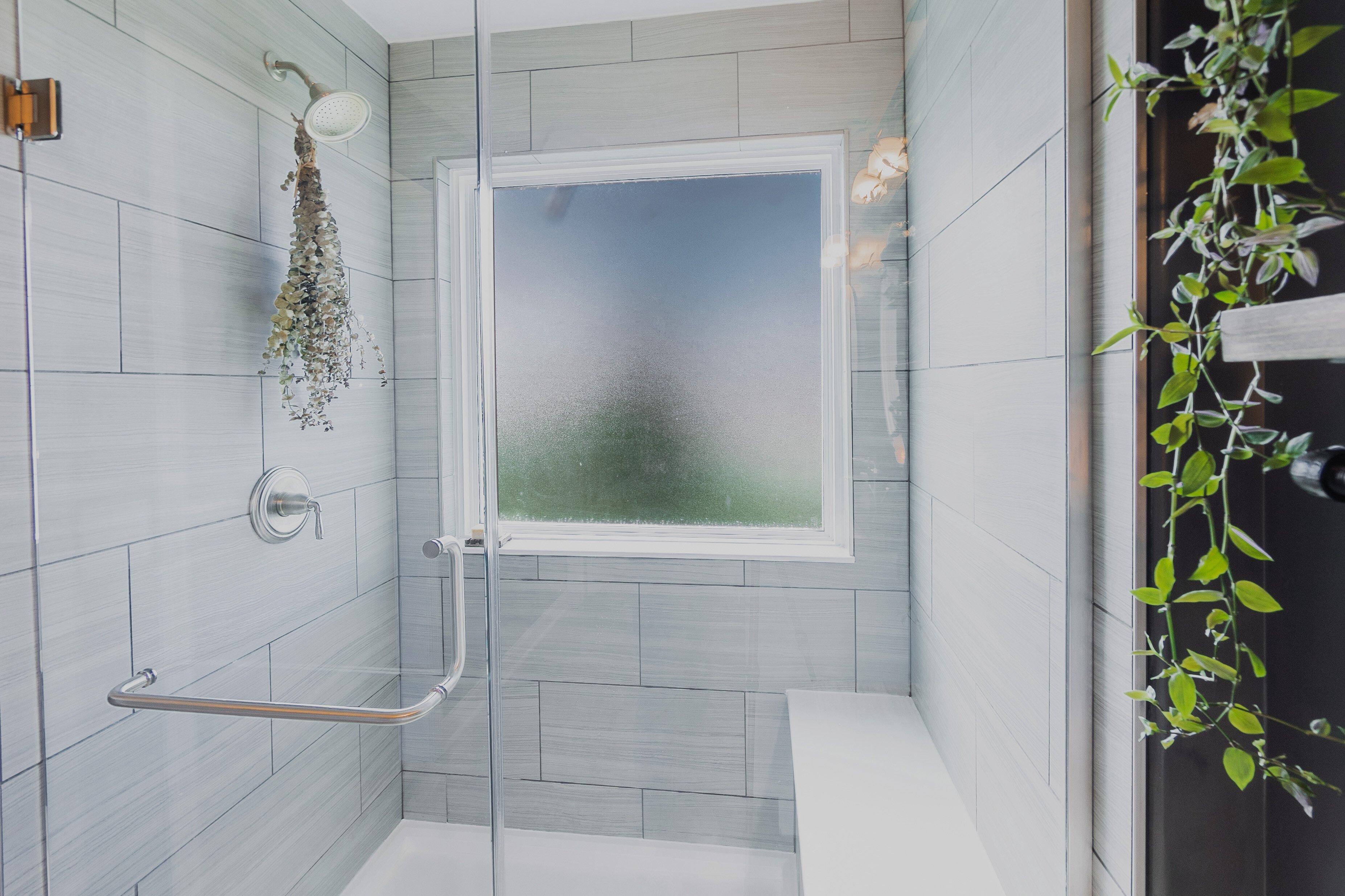Large grey tile with dark grout with a shower bench